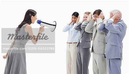Woman yelling in a megaphone at business people against white background Woman yelling in a megaphone at business people against white background