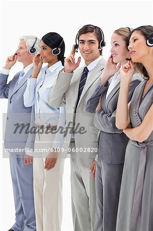 Professionals in suits listening with headsets against white background