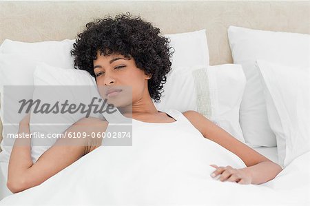 Curly haired woman waking up in a white bed
