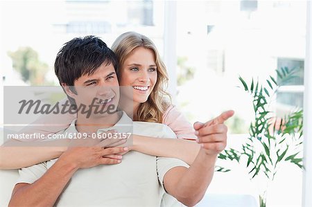 A man and woman hold hands while smiling as the man points something out to the woman.