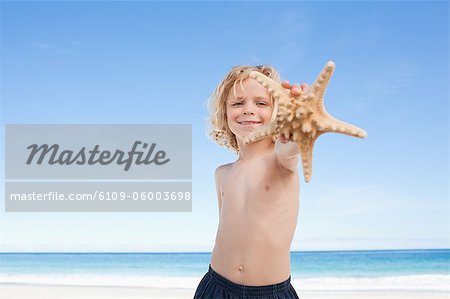 Cute little boy on the beach showing his starfish