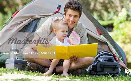 A smiling father smiles looking forward as the boy turns the page