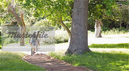 A boyfriend and girlfriend cycle together down a path