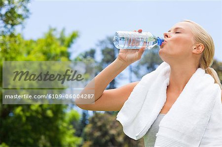 Side view of young sportswoman drinking water