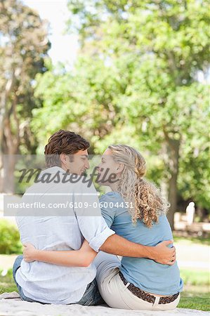 Rear view of a smiling young couple sitting in the park