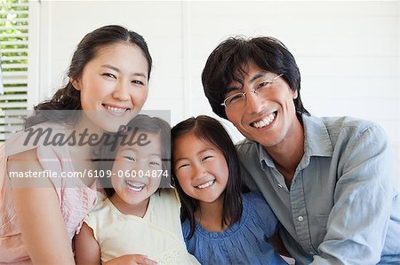 The entire family sitting together on the couch while smiling