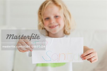 Focus on the letter to santa being held by a small boy.
