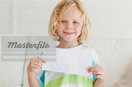 A smiling boy holds in his hands his letter to santa.