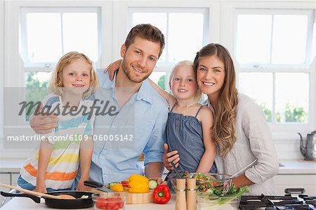A smiling family all in the kitchen as they begin to prepare dinner