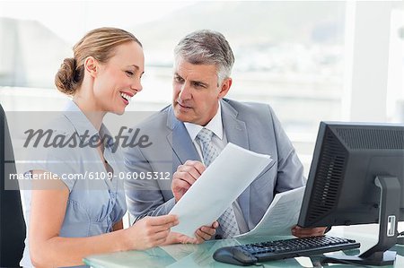 Boss giving files to his employee in a bright office