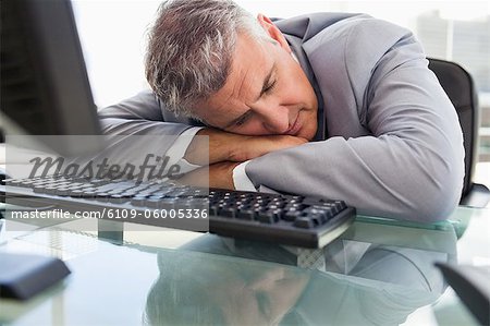 Businessperson Sleeping On His Desk In His Office Stock Photo