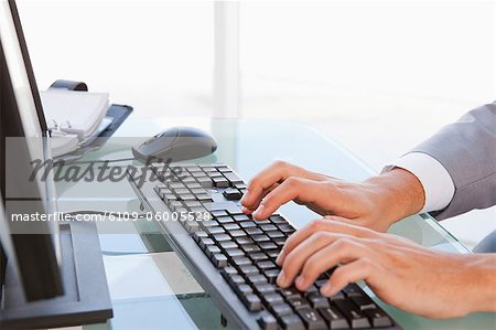 Close-up of a businessman typing on his keyboard in a bright office