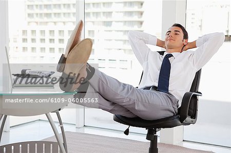 https://image1.masterfile.com/getImage/6109-06005563em-happy-businessman-feet-on-his-desk-in-a-bright-office-stock-photo.jpg