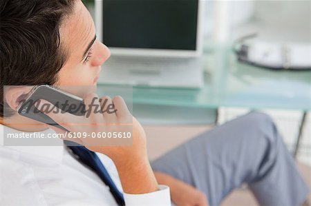 Rear view of a handsome businessman phoning in a bright office