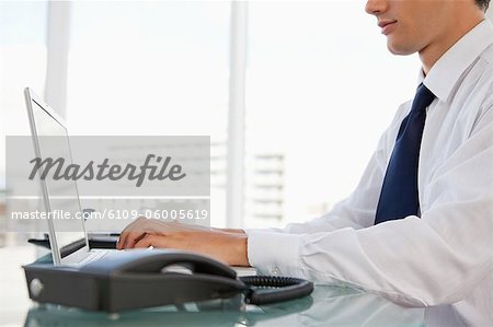 Close-up of a businessman working on a laptop in a bright office