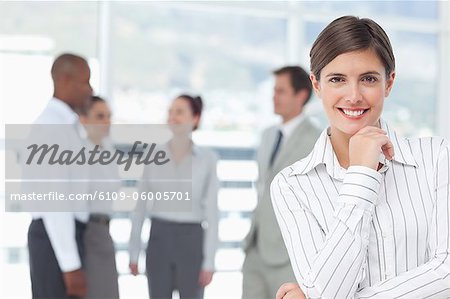 Smiling young saleswoman with associates behind her