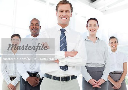 Smiling young businessman with arms folded and his team