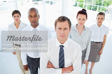 Salesman with his arms folded standing with his team