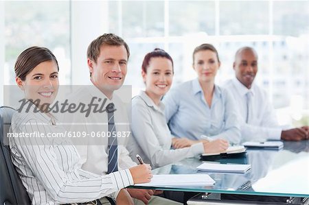 Side view of smiling young salespeople sitting at a table