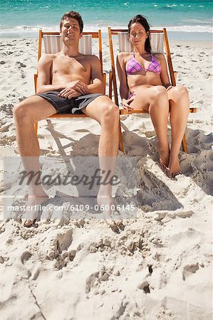 Lovers taking a sunbath on the beach with the ocean in bakground