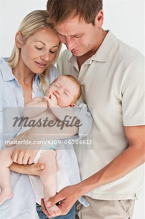 Mother and father with their baby against a white background