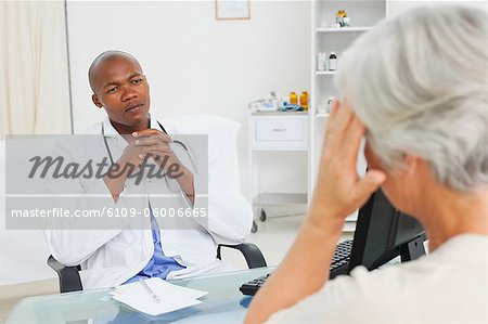 Male doctor listening to his mature patient