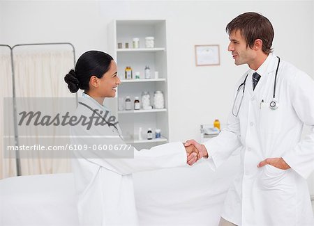 Young smiling surgeons shaking hands in agreement in a hospital room