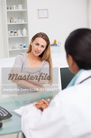 Patient explaining her pain to her doctor by holding her elbow