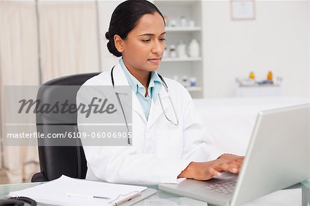 Serious practitioner sitting at her desk while working with her laptop