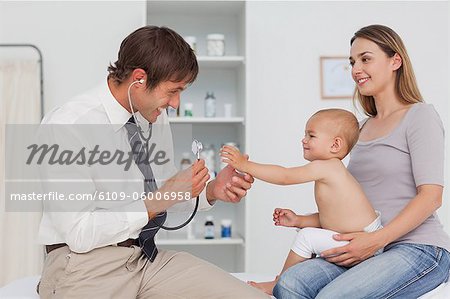 Smiling baby extending her little hand while being examined by her practitioner