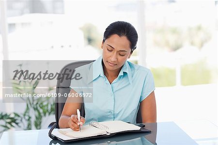 Serious secretary working with a ring binder folder while sitting at a desk