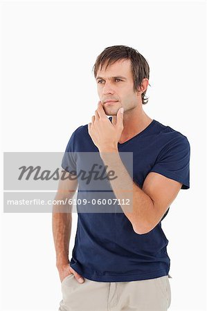 Serious man looking away while standing up with his fingers placed on his chin
