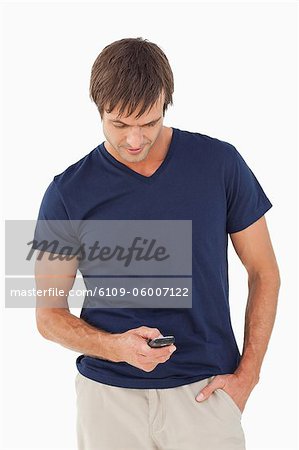Relaxed man sending a text with his mobile phone against a white background