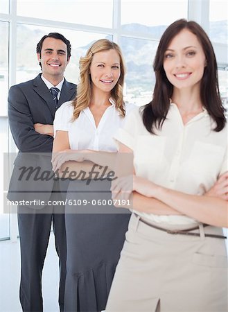 Man and two women smiling as they stand behind each other with their arms crossed