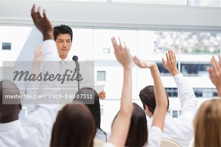 Businessman looking ahead of him as he is being watched by an audience with their arms raised