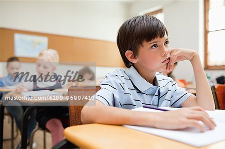 Thinking Elementary Student Sitting At His Desk Stock Photo