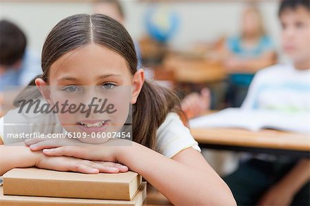 Primary student leaning on a pile of books