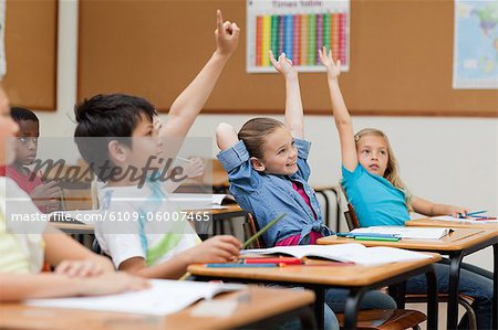 Side view of students raising their hands