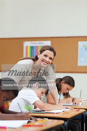 Side view of helpful elementary teacher next to a student