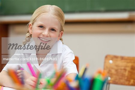 Smiling elementary student sitting at desk with pen