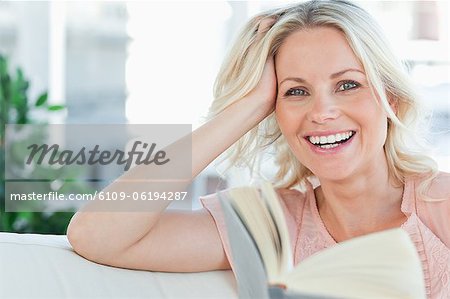 Blonde female laughing with a book
