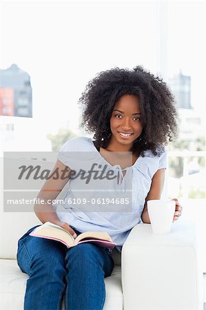 Portrait of a woman holding a cup and reading a book