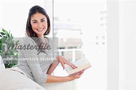 Portrait of a cute brunette holding a novel