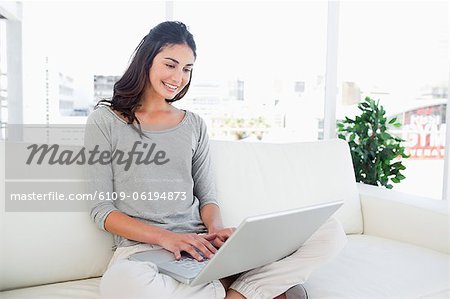 Smiling brunette using a laptop