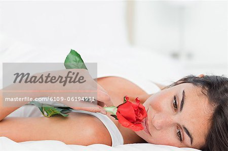 Beauty lying on her back while smelling a rose