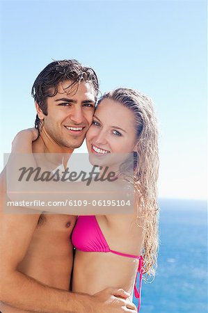 Side view of smiling couple hugging in the pool