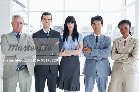 Five serious business people standing upright in a well-lit room