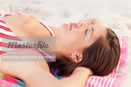 Woman sunbathing while lying on a towel
