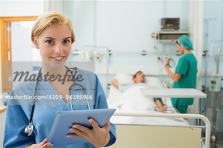 Blonde nurse holding a tablet computer while smiling