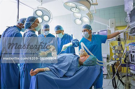 Team of surgeons operating an unconscious patient